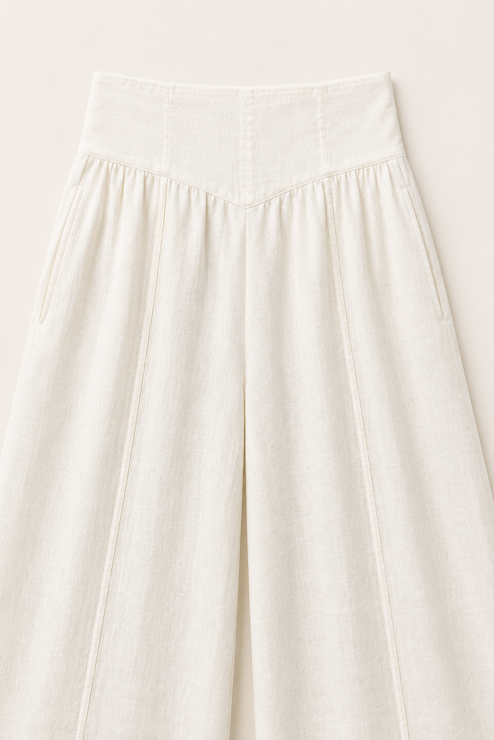A close-up of a high-waisted, wide-leg skirt in a textured off-white linen fabric, showing the waistband and pleated front panels.