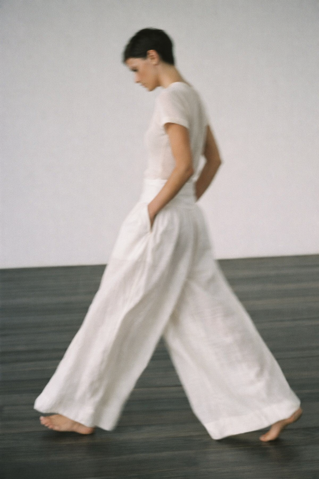 Person wearing a white outfit walking on a plain background