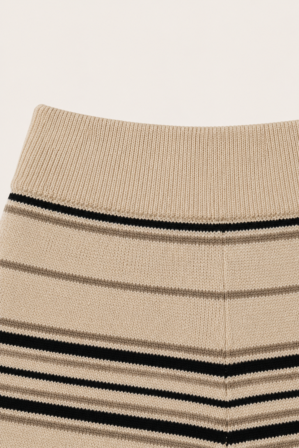 Close-up of a ribbed knit waistband in beige with horizontal black and taupe stripes.